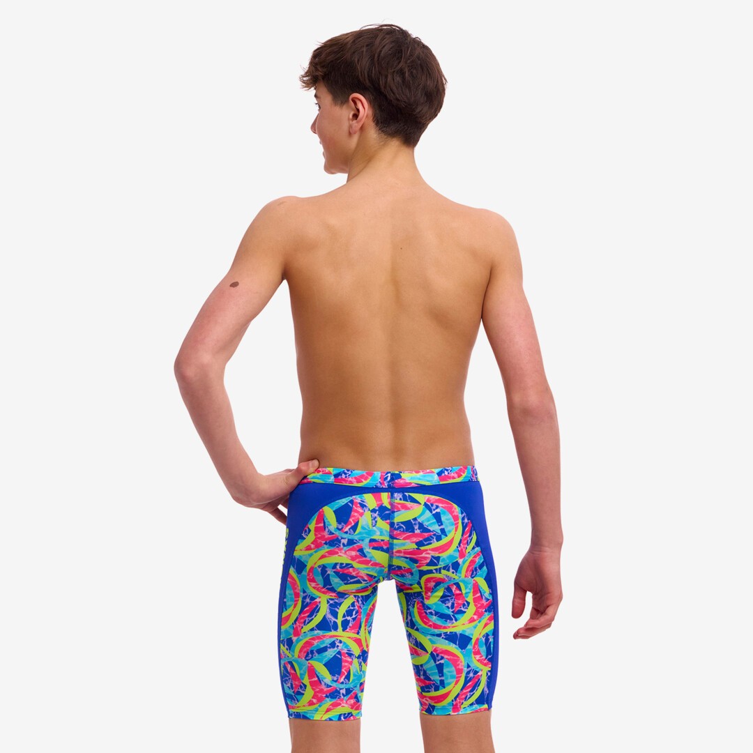 Back view of a boy wearing multicolored Funky Trunks Choppy Waters training jammers with the Funky Trunks brand logo on the leg.