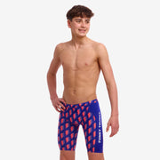 A boy wearing blue and red Funky Trunks Flash Boy's Training jammers with a wide elastic waistband and leg openings.