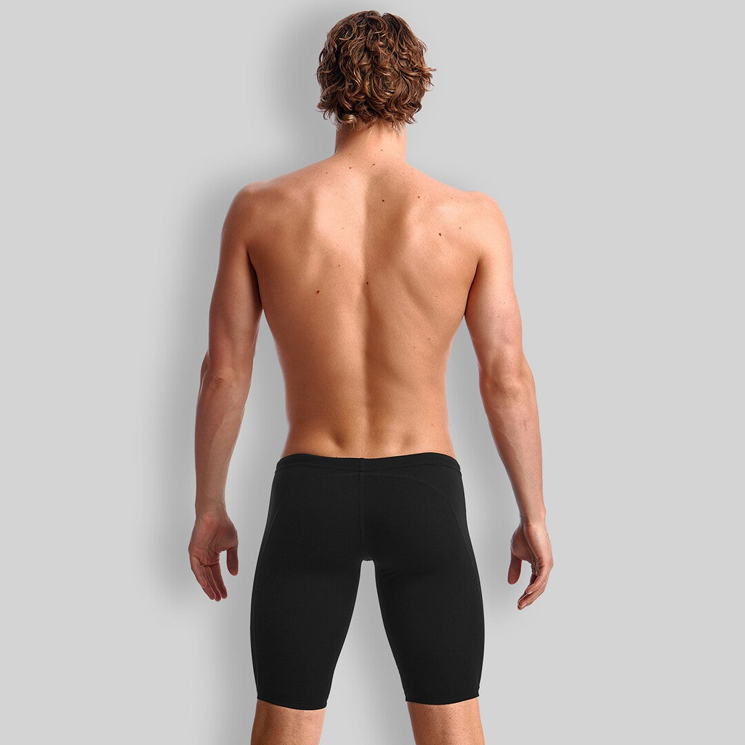 Back view of a man standing wearing black Funky Trunks jammers.