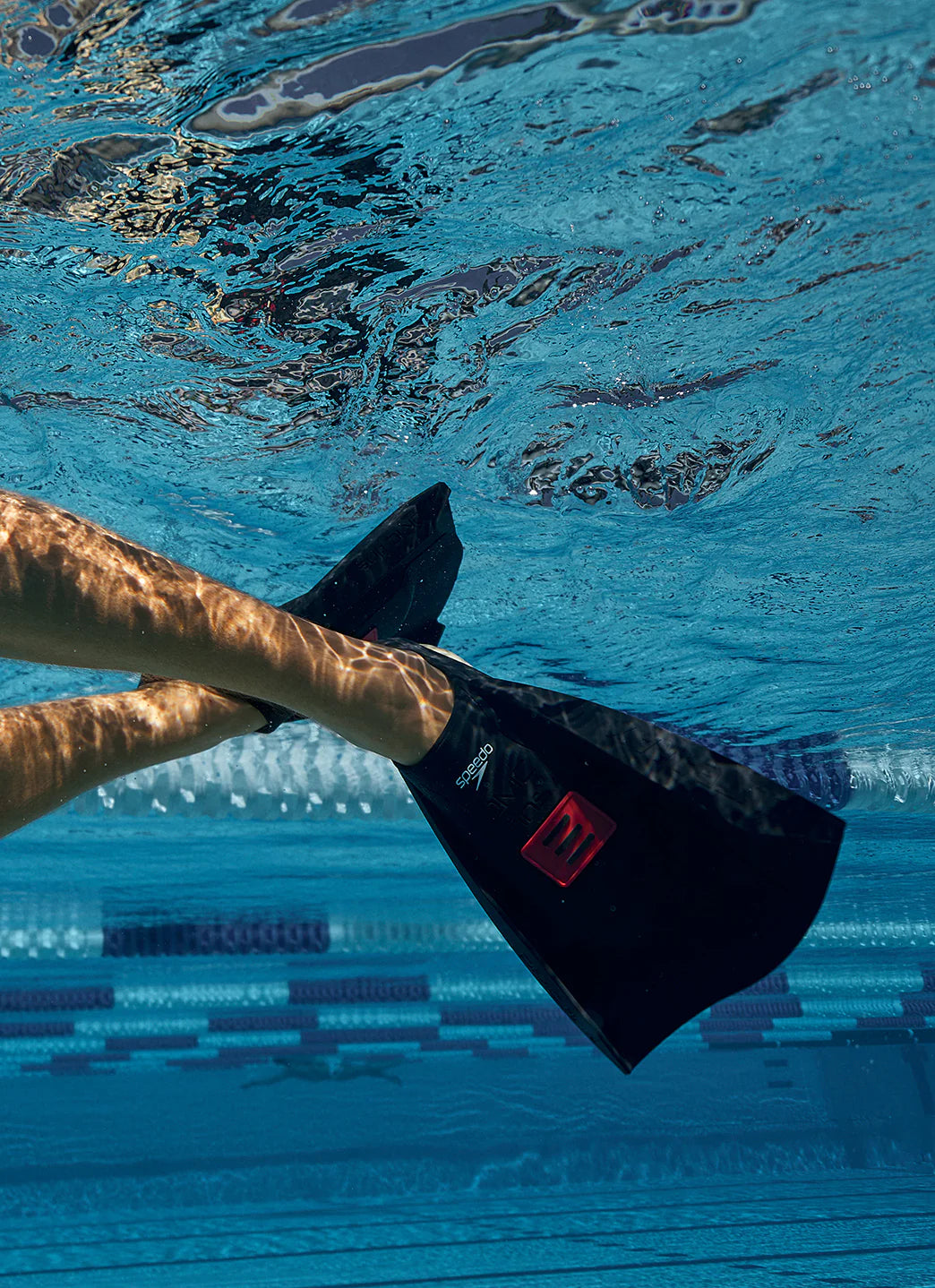 Close up photo of a pair of anthracite black/red dmc elite max fins in the water.