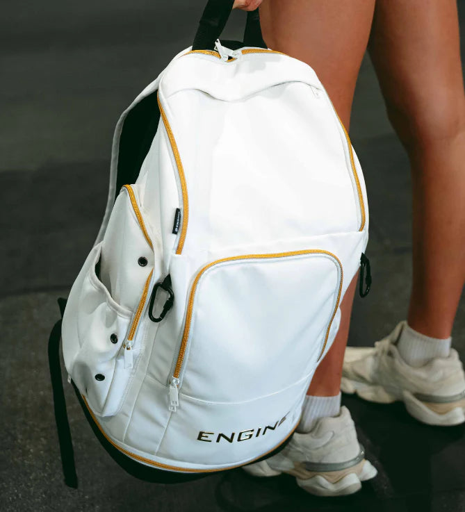 Person holding a white backpack with gold accents and gold "Engine' branding