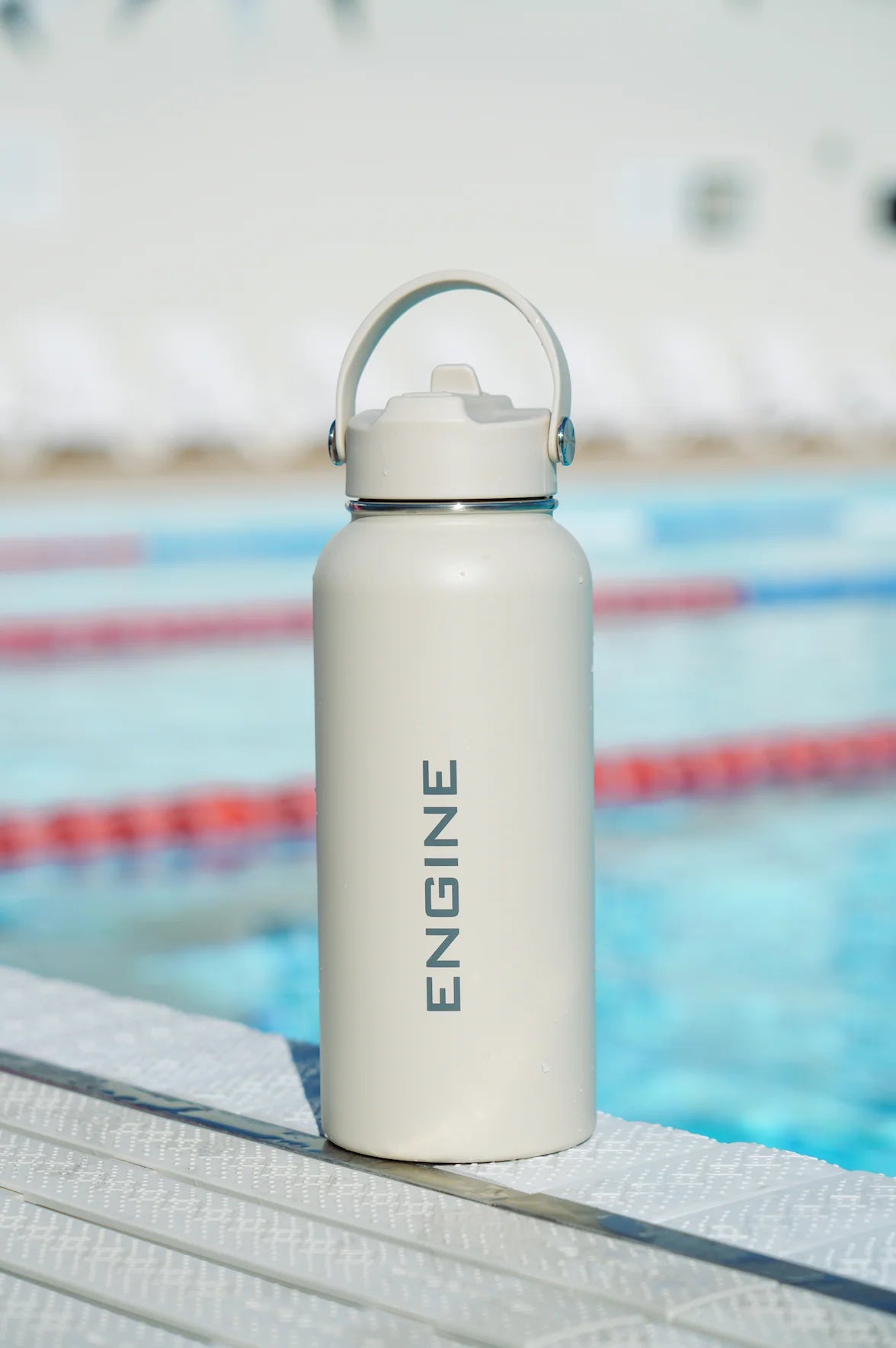 An ivory coloured insulated water bottle with a matching lid and carrying loop, featuring the word 'ENGINE' printed vertically in white.