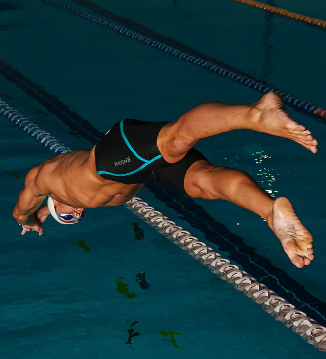 Male swimmer wearing 'Engine' black racing jammers with blue accents, diving into a pool