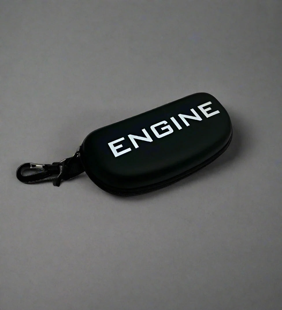 Side view of swim goggle case, "ENGINE" branding, black with black trim, zipper closure, clip for attachment.