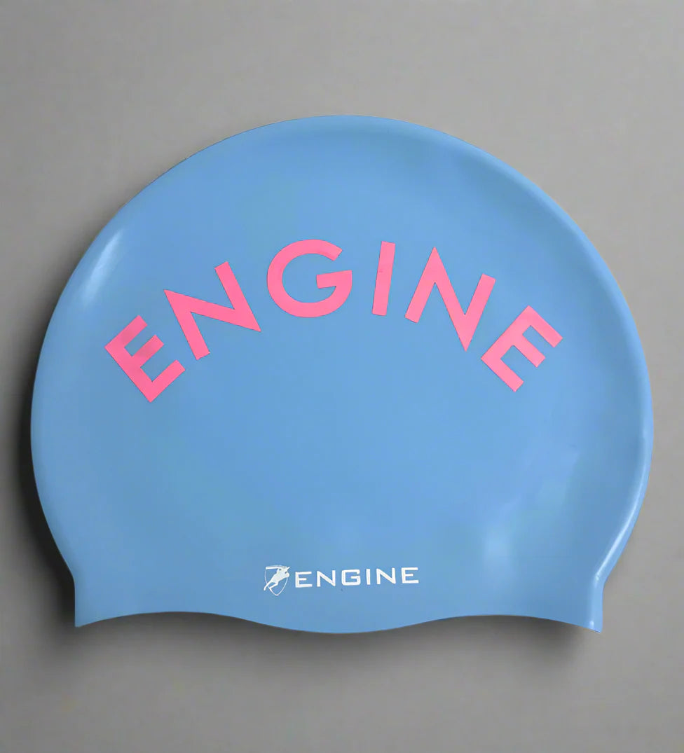 Cornflower blue swim cap with pink 'ENGINE' writing on a grey background