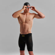 A man wearing Funky Trunks Black Attack Men's Apex Viper Jammers with a black Funky Trunks swim cap, adjusting his goggles.