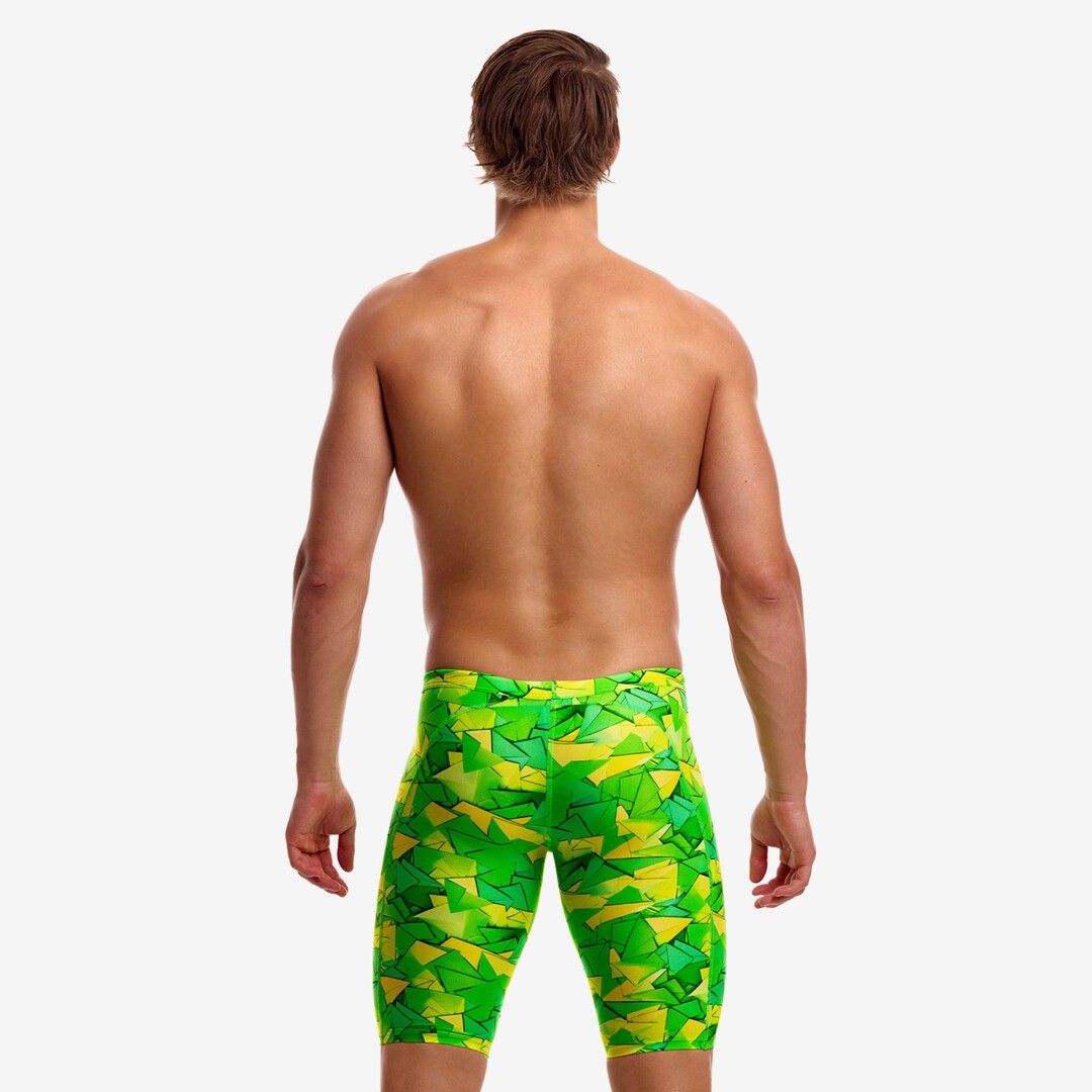 A shirtless male viewed from behind wearing bright green and yellow geometric patterned pair of swimming jammers from Funky Trunks.