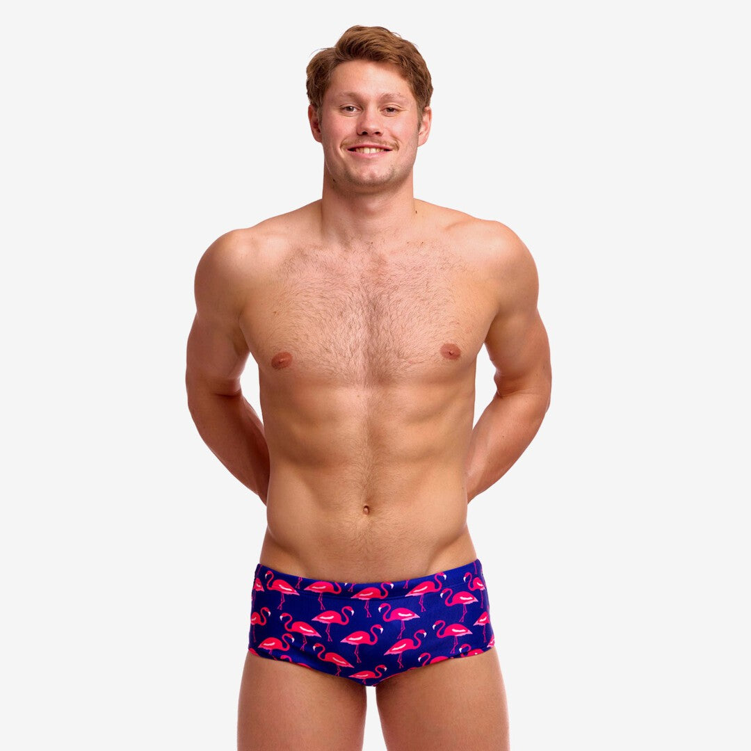Man wearing blue swim trunks with pink flamingo pattern on a white background