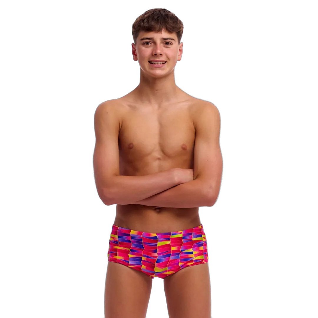 Boy wearing pink, purple and yellow colourful swim trunks on a white background