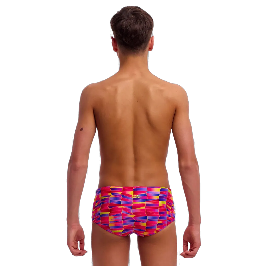 Back view of a boy wearing pink, purple and yellow colourful swim trunks on a white background