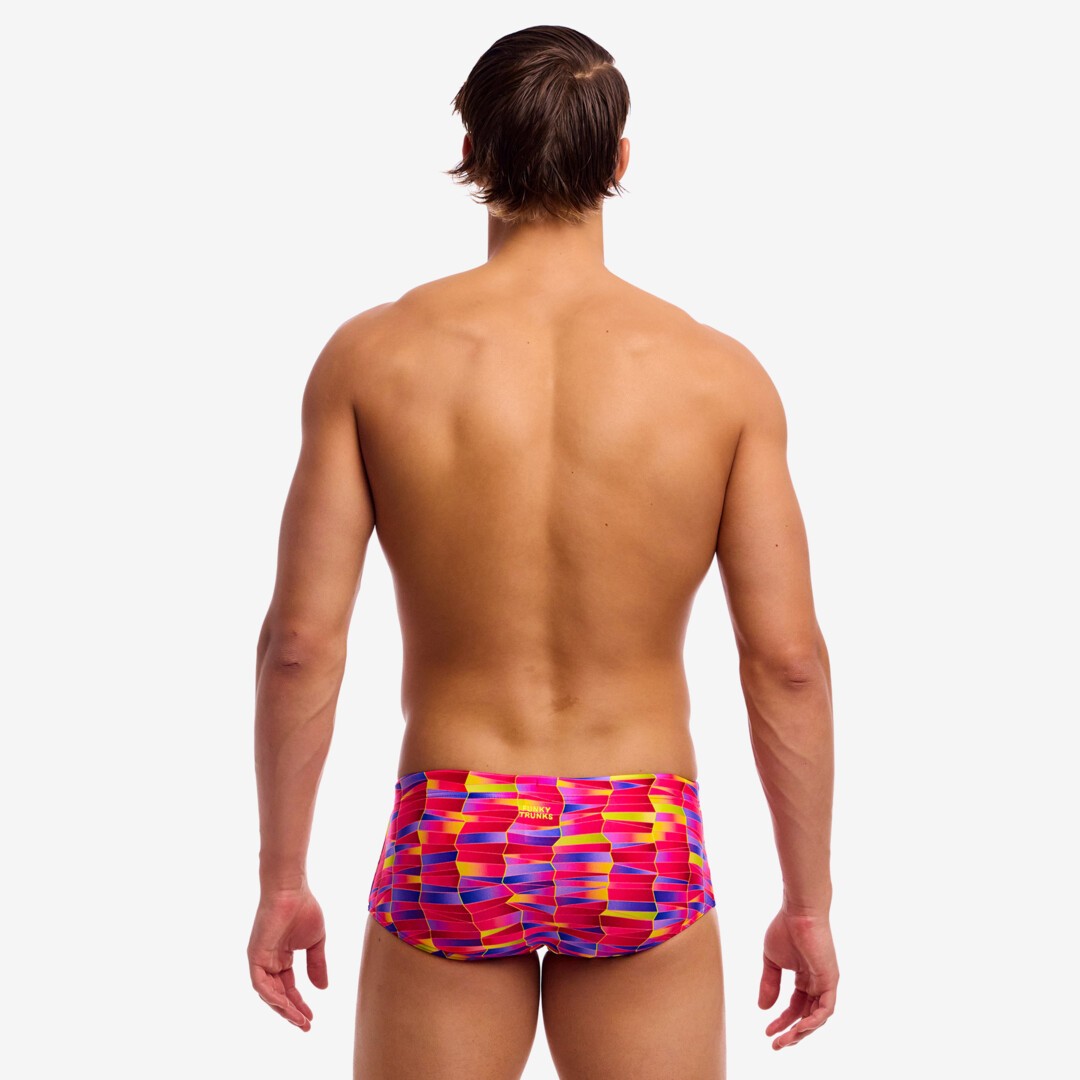 Back view of a man wearing colourful pink, purple and yellow swim trunks on a white background