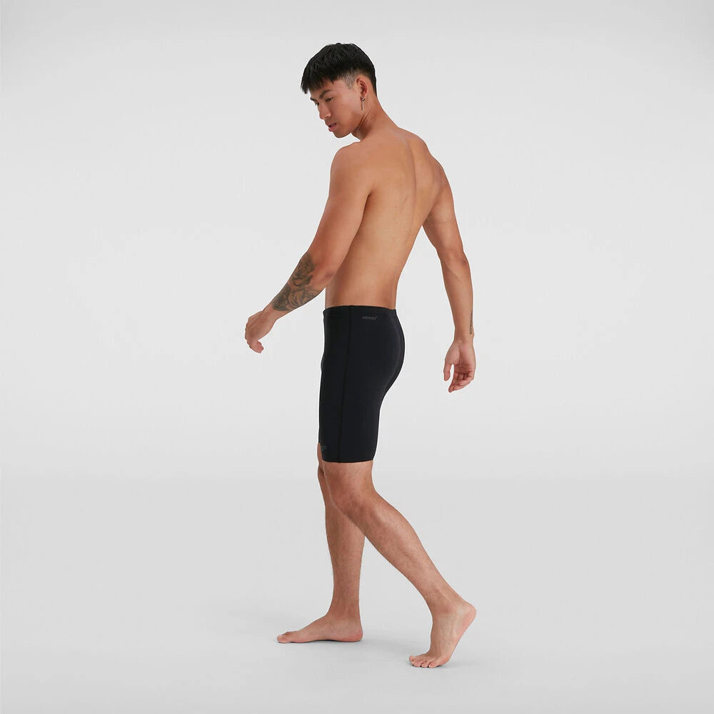 A man posing sideways wearing black Speedo jammers.