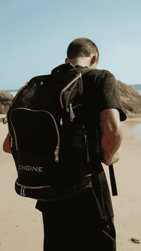 Black Engine Elite backpack being worn by a man on the beach