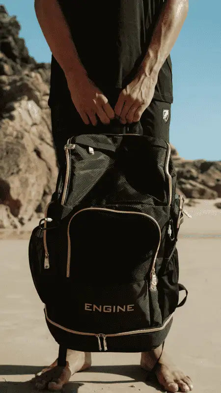 Black Engine Elite backpack being held by a man on the beach