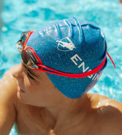 Person wearing a blue swim cap and red goggles in a pool