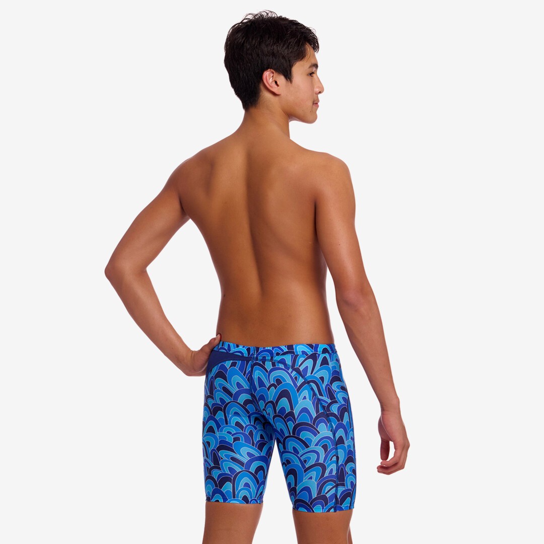 Back view of a person wearing blue patterned swim jammers on a white background