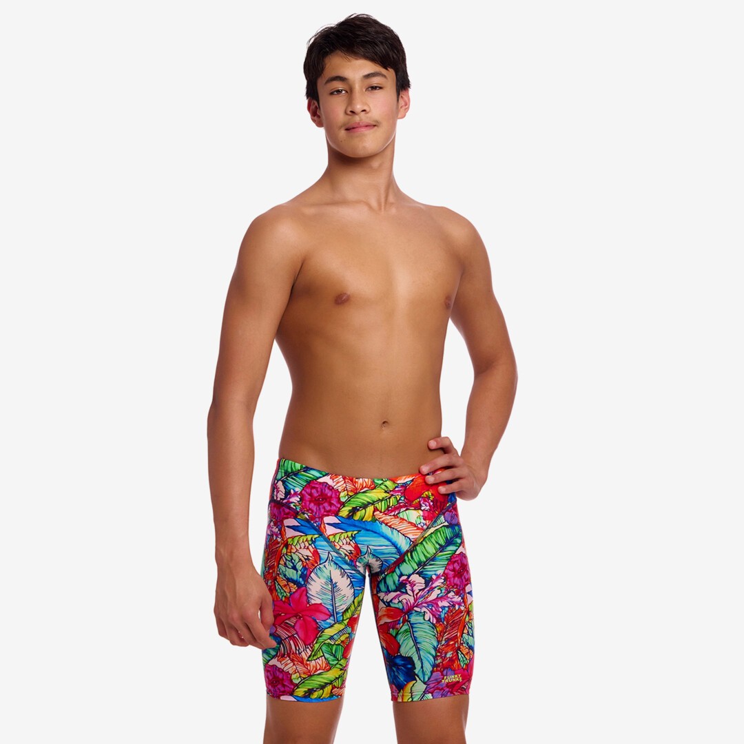 A male model wearing colourful tropical print swim jammers against a plain white studio background.