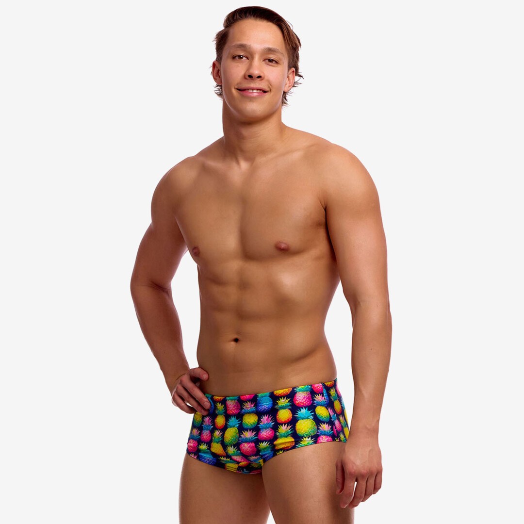 Man wearing colourful pineapple-patterned swim trunks on a white background