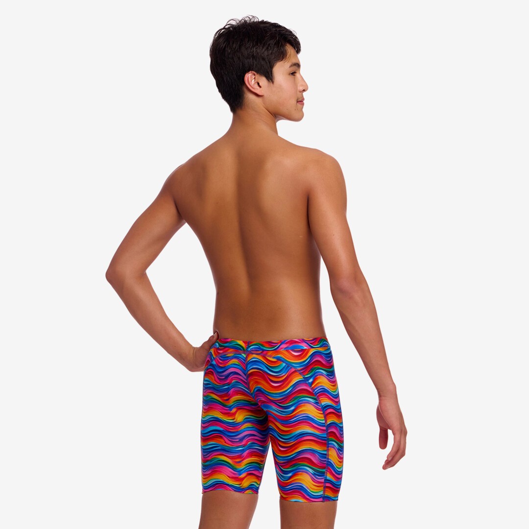 Back view of a person wearing colourful wave patterned swim jammers on a white background