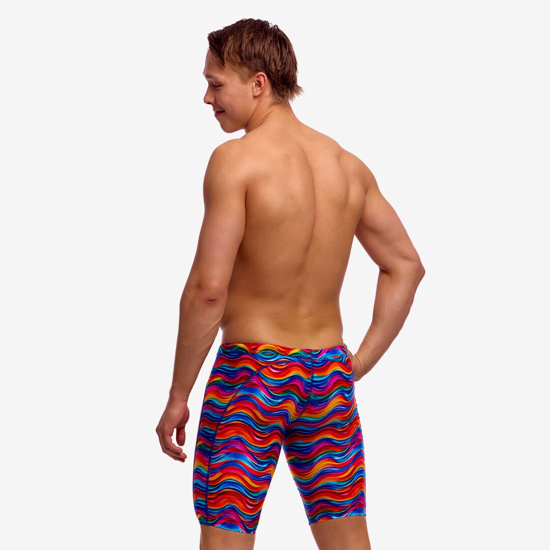 Man wearing colourful wave patterned swim jammers on a plain background