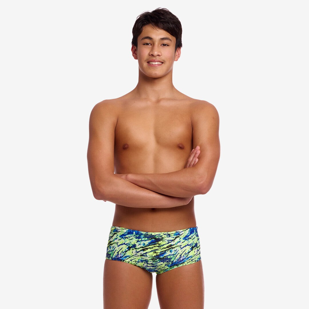 Boy wearing colourful blue and green swim briefs on a white background