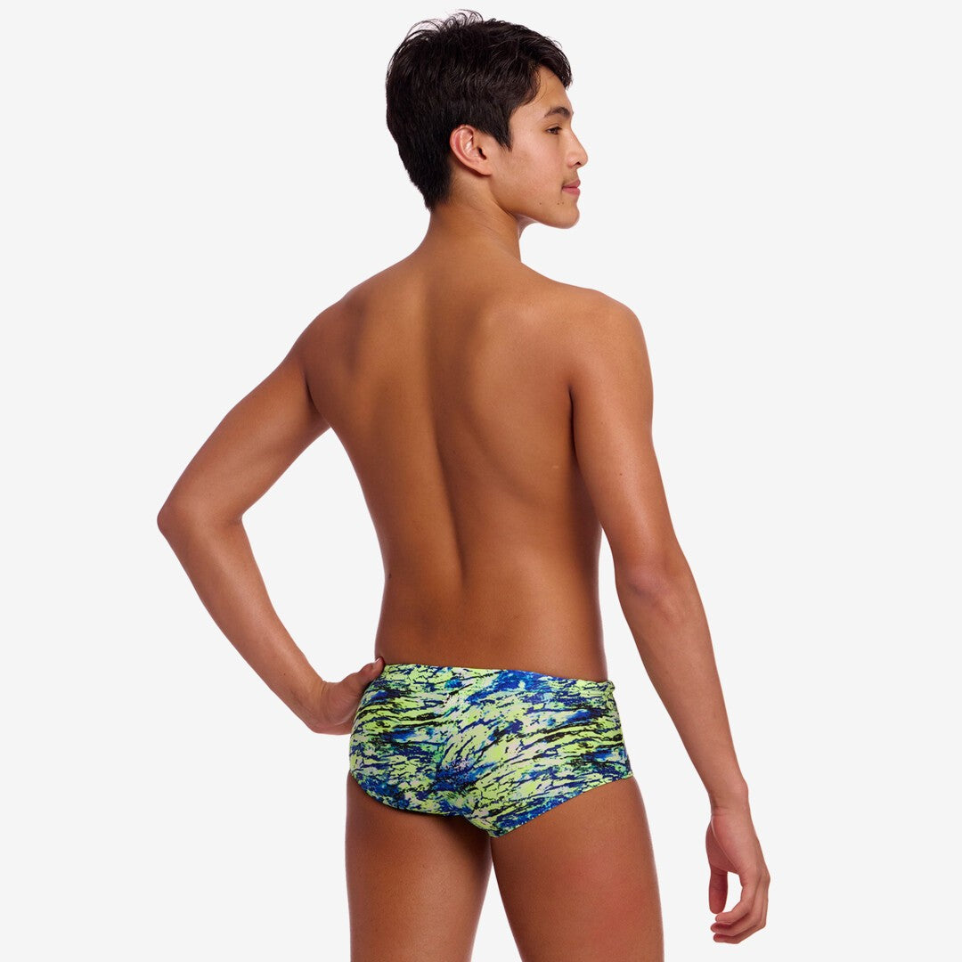 Back view of a boy wearing colourful blue and green swim briefs on a white background