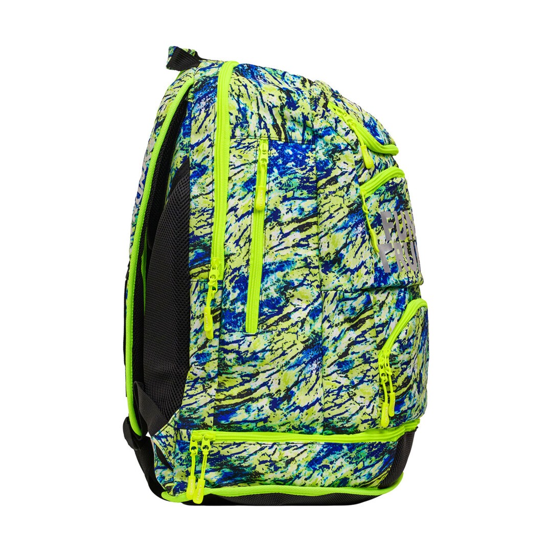 Side view of a colourful blue and green backpack with multiple zips and 'Funky Trunks' branding on a white background