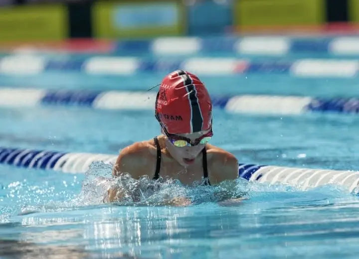 Girl swimming in a pool with a swim cap and goggles