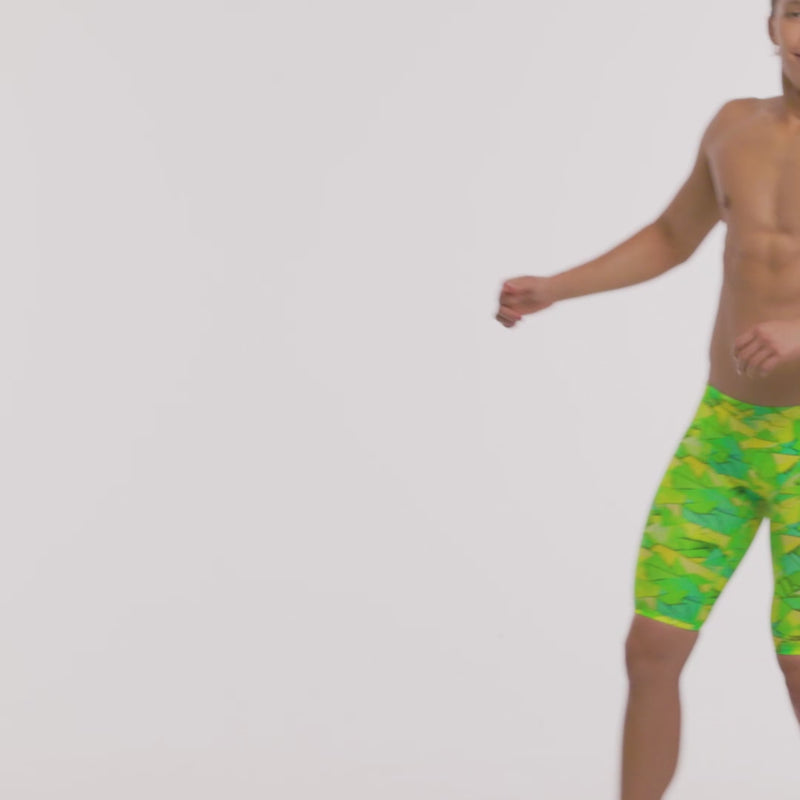 A man bouncing around wearing bright green and yellow "Try tonic" patterned swimming jammers from Funky Trunks