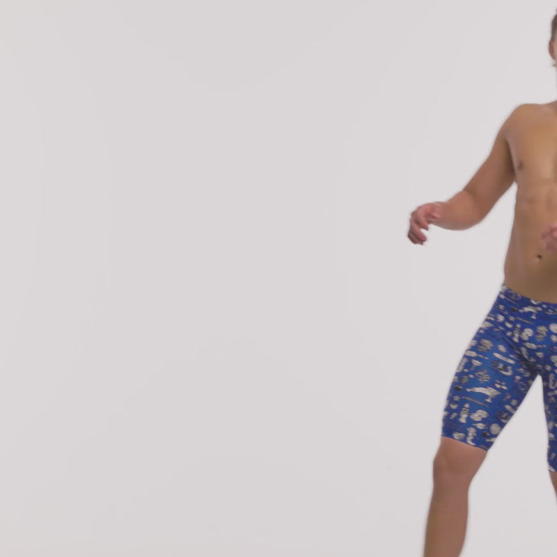 A shirtless man jumping and having fun wearing blue swimming jammers with a white "scratchy" pattern from Funky Trunks.
